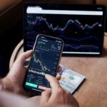 man looking at the stock charts on the phone and tablet