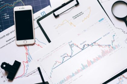 Stock market analysis setup with charts, phone, magnifier, and clipboards. — Photo by Leeloo The First on Pexels