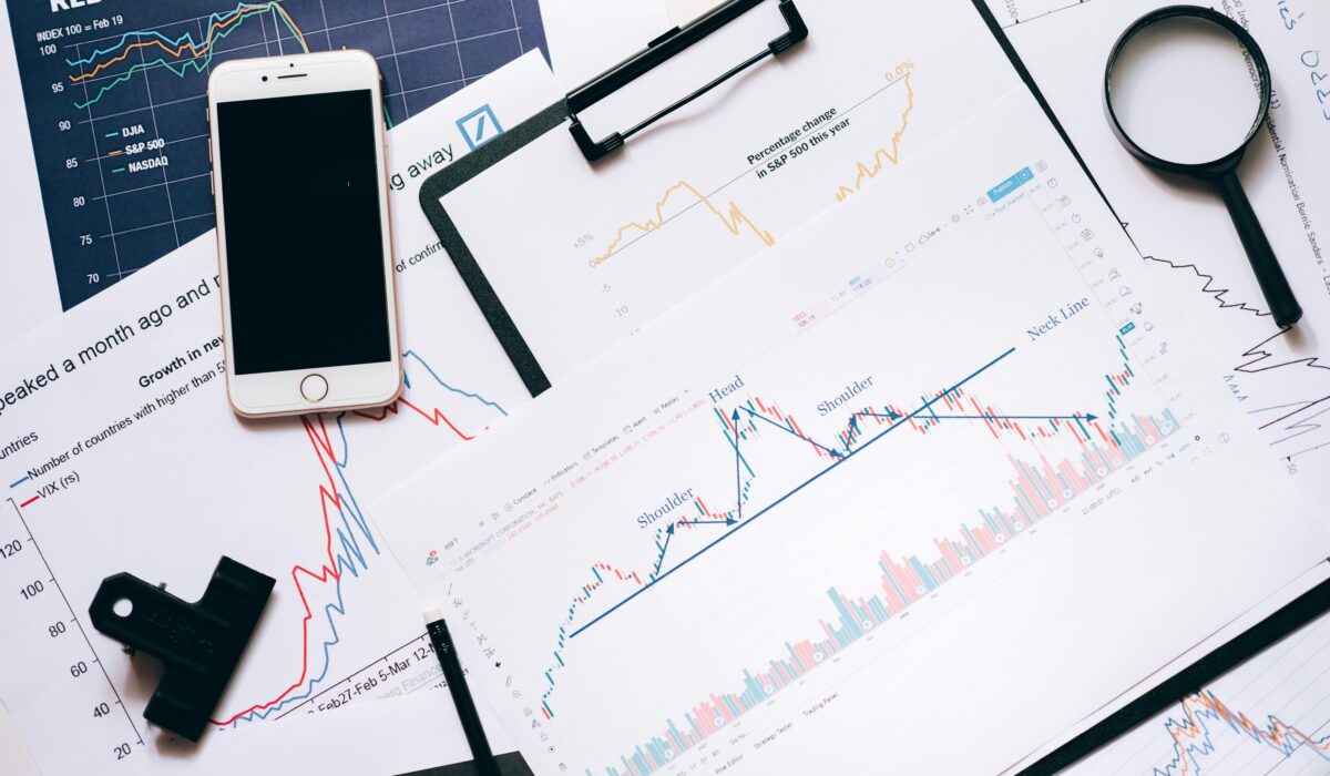 Stock market analysis setup with charts, phone, magnifier, and clipboards. — Photo by Leeloo The First on Pexels